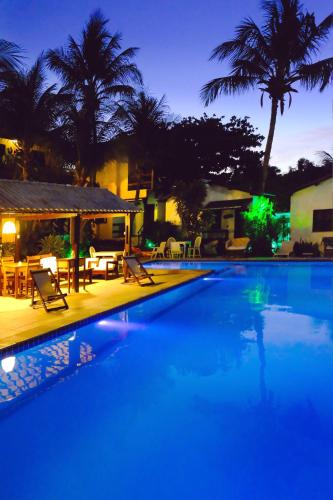 a large swimming pool with chairs and tables at night at Hotel e Pousada La Dolce Vita in Canoa Quebrada