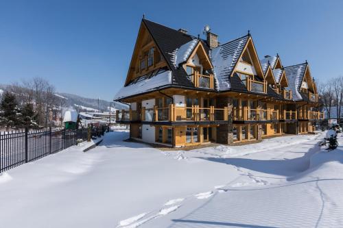 a large wooden house in the snow with snow covered yard at Rezydencja Zakopiańska in Zakopane