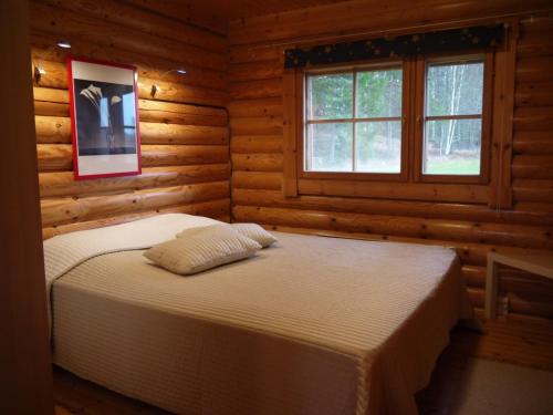a bedroom with two beds in a log cabin at Hotel Hanhi Cottages in Lapinjärvi