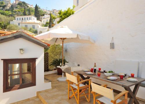 a patio with a table and chairs and an umbrella at Hydra Optima in Hydra
