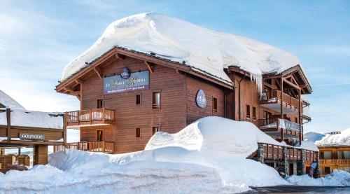 a building covered in snow next to a pile of snow at CGH Résidence Boutique Le Lodge Hemera in La Rosière