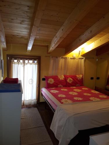una camera da letto con un letto con un piumone rosso e una finestra di Dora Baltea Monolocale primo piano Mansarda secondo piano a Verona