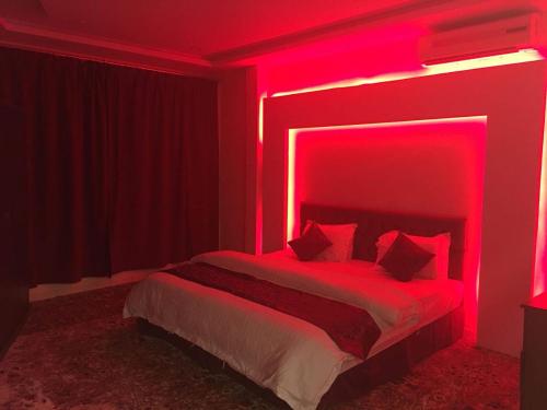 a bedroom with a bed with a red lighting at Orchid Tarif Serviced Apartments 1 شقق أوركيد طريف للشقق المخدومة 1 in Ţurayf