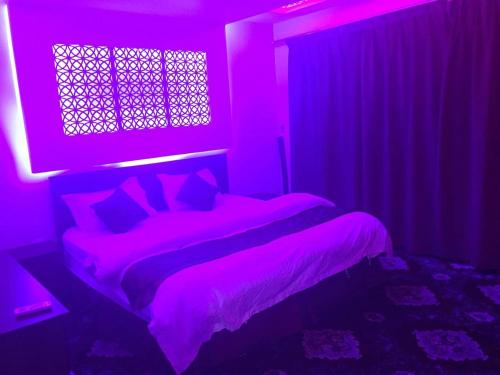 a purple bedroom with a bed and a window at Orchid Tarif Serviced Apartments 1 شقق أوركيد طريف للشقق المخدومة 1 in Ţurayf