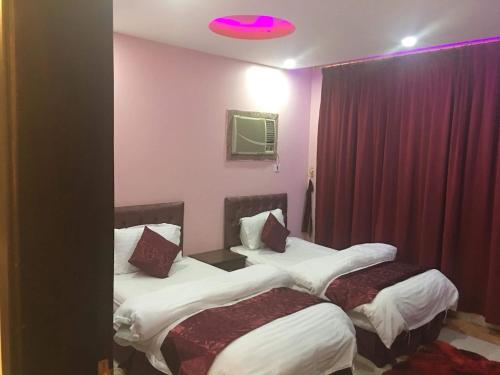 a hotel room with two beds and a purple light at Orchid Tarif Serviced Apartments 1 شقق أوركيد طريف للشقق المخدومة 1 in Ţurayf
