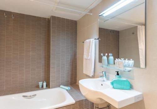a bathroom with a sink and a tub and a mirror at Hotel Salou Beach Family Rentalmar in Salou