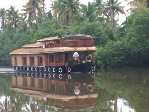a boat on a river with palm trees in the background at Mango Kerala Homes in Kumarakom