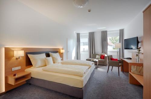 ein Hotelzimmer mit einem großen Bett und einem Schreibtisch in der Unterkunft Hotel Villa Dürkopp in Bad Salzuflen
