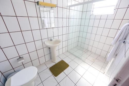 a white tiled bathroom with a toilet and a sink at Hotel Mos São José in São José