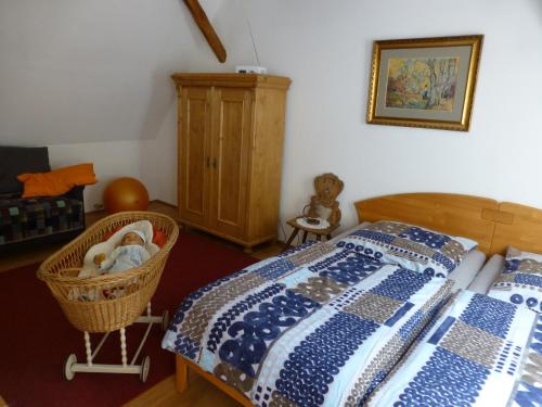 ein Schlafzimmer mit einem Bett und einem Korb mit einem Kinderbett in der Unterkunft Feriengaleriewohnung Im Denkmal Stilvoll-Komfortabel Baubiologisch in Erlenbach