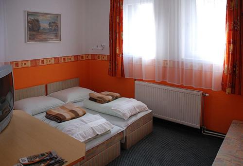 2 camas en una habitación con paredes de color naranja en Hotel Flóra**, en Orosháza