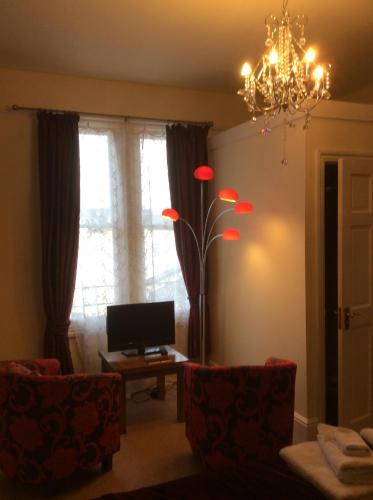 a living room with a chandelier and red chairs at Cheltenham Lawn and Pittvile Gallery in Cheltenham