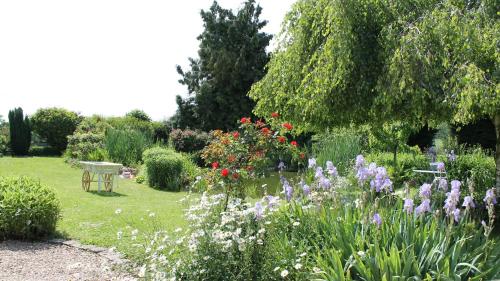 a garden with flowers and a bench in the grass at gîte du Clos Sébastien in Beautheil