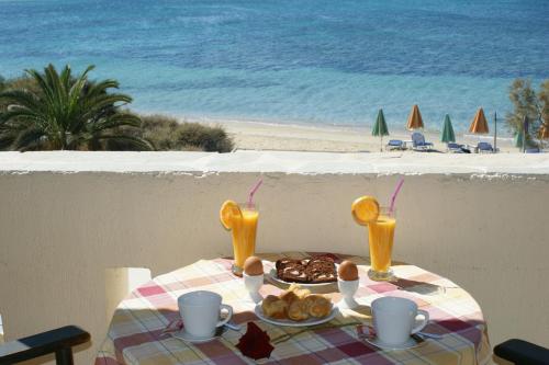 una mesa con un plato de comida y dos vasos de zumo en Verykokkos on the beach, en Agia Anna de Naxos