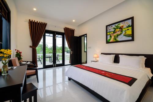 a bedroom with a large bed and a desk at The Son Villa Hoi An in Hoi An