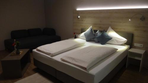 a bedroom with a bed with white sheets and blue pillows at Seegasthof Breineder - Familien & Seminarhotel in Mönichwald