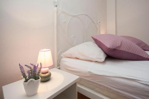a bed with purple pillows and a table with a lamp at Rooms Katarina in Lozovac