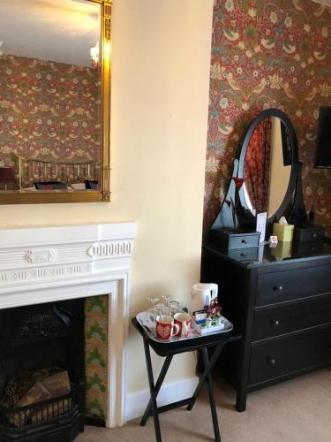 a room with a fireplace and a mirror and a table at The Langtons in Eastbourne