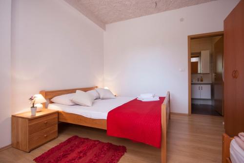 a bedroom with a bed with a red blanket at Rooms Katarina in Lozovac