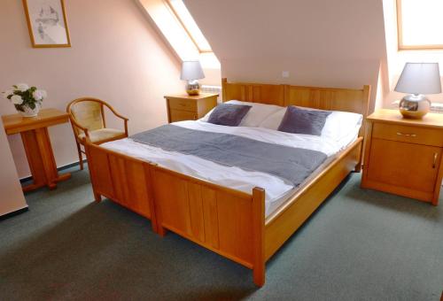 1 dormitorio con cama de madera y silla en Penzion Moravský sommeliér en Valtice