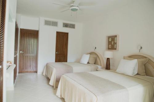 two beds in a room with white walls at Las Villas Akumal in Akumal