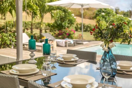 a table with plates and candles on it next to a pool at Villas Palm in Le Vauclin