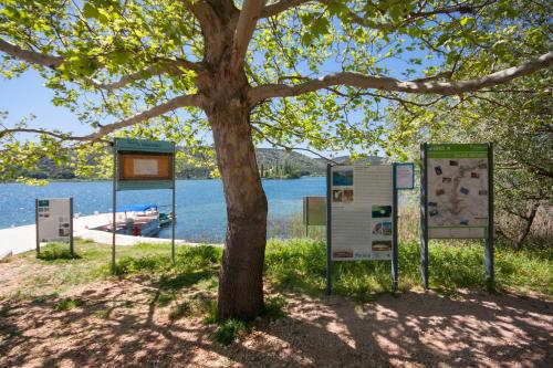 a tree with signs in front of a lake at Rooms Katarina in Lozovac