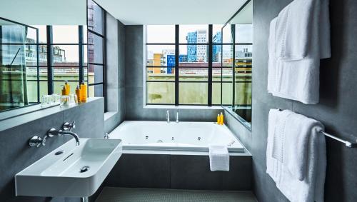 y baño con bañera, lavabo y ventanas. en New Road Hotel en Londres