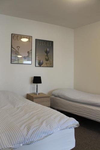 a bedroom with two beds and a night stand with two lamps at Odense Apartments in Odense