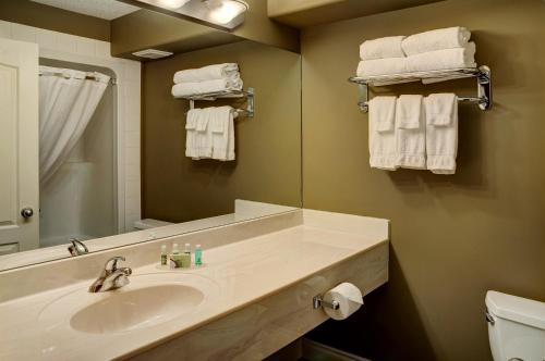uma casa de banho com lavatório, espelho e toalhas em Lakeview Inns & Suites - Edson Airport West em Edson
