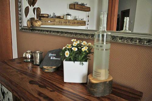 una mesa de madera con una botella y flores. en Ehem. Sächsisch-Bayrischer Hof, en Pöhl