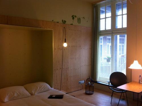 a bedroom with a bed and a table and a window at LABnul50 self check-in hotel Groningen in Groningen