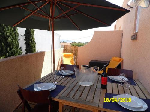 - une table en bois avec un parasol sur la terrasse dans l'établissement T1 DE CHARME Terrasse VUE MER, à Bandol