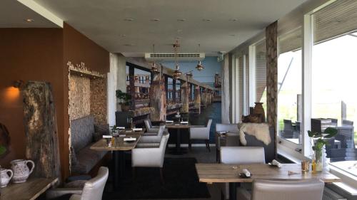 a restaurant with wooden tables and chairs and a corridor at Appartement Zilte Lucht in Wilhelminadorp