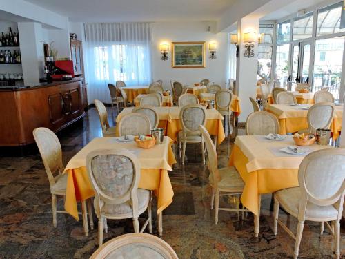 a dining room with tables and chairs with yellow table cloth at Hotel Capri in Lesa