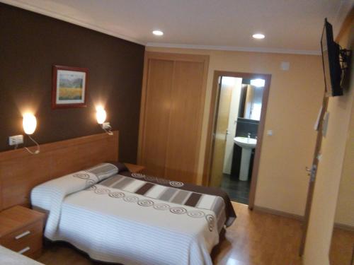 a bedroom with a bed and a door to a bathroom at Hostal Lido in Ourense