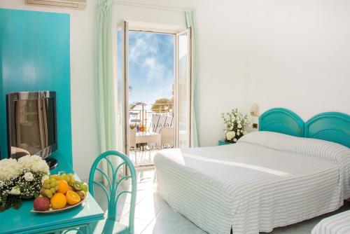 a bedroom with a bed and a table with a bowl of fruit at Hotel Capizzo in Ischia