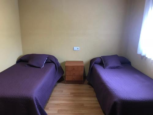 two beds in a room with purple sheets at Pensión la Estación in Nubledo