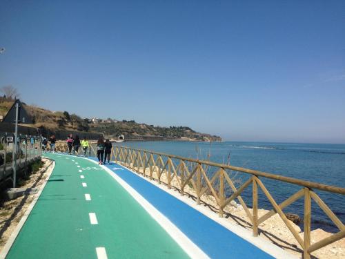 a person walking along a walkway next to the water at Agriturismo Villa Vetiche in Rocca San Giovanni