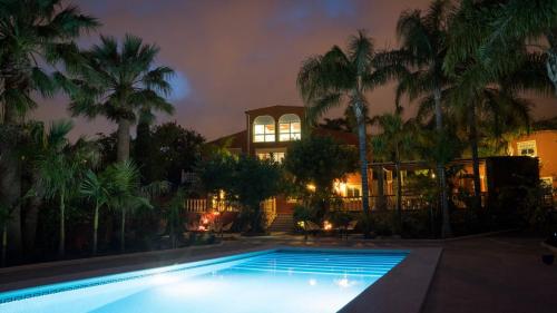 a swimming pool in front of a house with palm trees at Finca La Vida Loca - Adults Only in Benalmádena