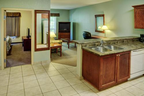 cocina con fregadero y sala de estar. en Lakeview Inns & Suites - Chetwynd, en Chetwynd