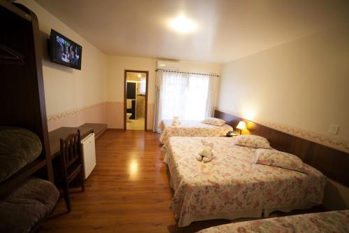 a bedroom with three beds and a tv on the wall at Pousada Vollweiter in Entre Rios
