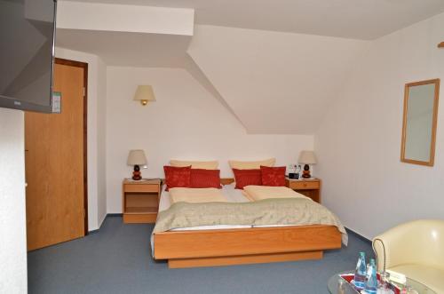 ein Schlafzimmer mit einem großen Bett mit roten Kissen in der Unterkunft Hotel-Landhaus Birkenmoor in Neuferchau