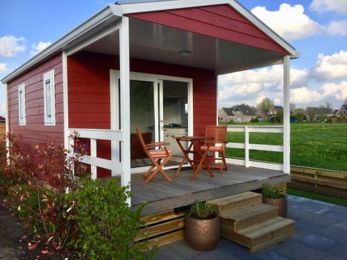 a red and white house with chairs and a table at Friesland-cottage in Molkwerum