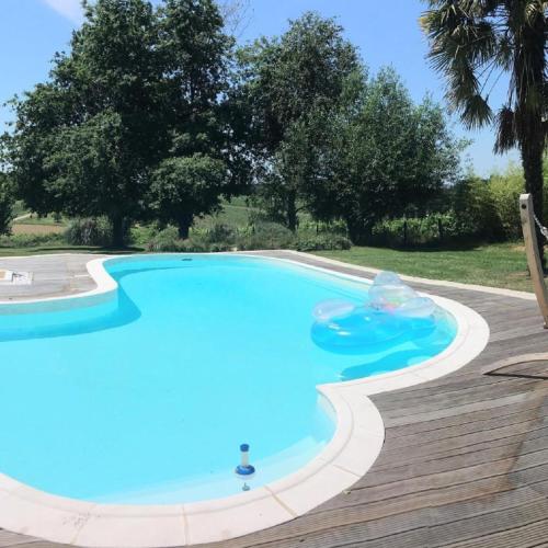une grande piscine bleue sur une terrasse en bois dans l'établissement La Porcherie, à Saint-Sernin
