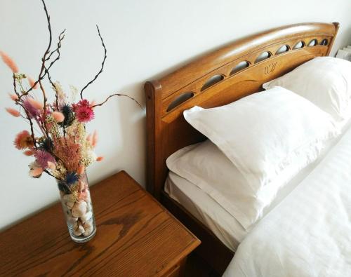 Loftik Apartments Abay street في ألماتي: مزهرية مع الزهور على طاولة بجوار سرير