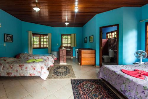 a bedroom with two beds and a blue wall at Pousada Terras do Poente in Vale do Capao