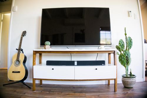 a living room with a large tv and a guitar at M&L Desert Cottage - 6 min To North Entry Of JTNP! in Twentynine Palms