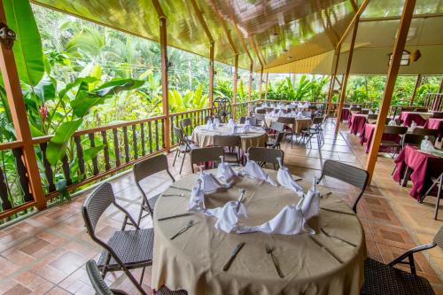 a dining room with tables and chairs on a balcony at Ara Ambigua Lodge in Sarapiquí