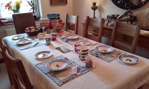 una mesa con platos y utensilios encima en Grovewood House Retreat en Kirkbean